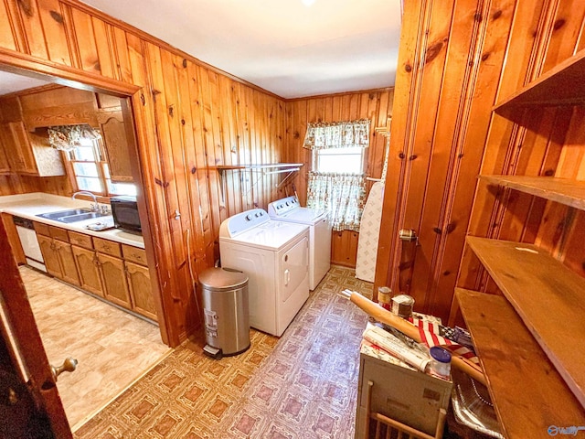 laundry room featuring wood walls, sink, washing machine and dryer, and plenty of natural light