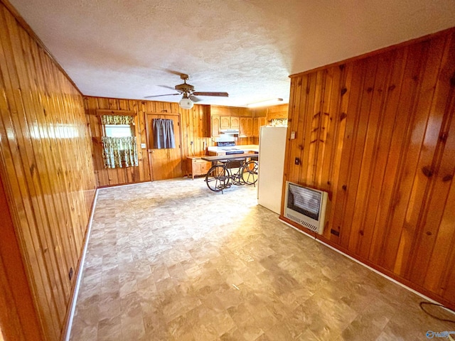 interior space with ceiling fan, wood walls, light tile patterned floors, and a textured ceiling