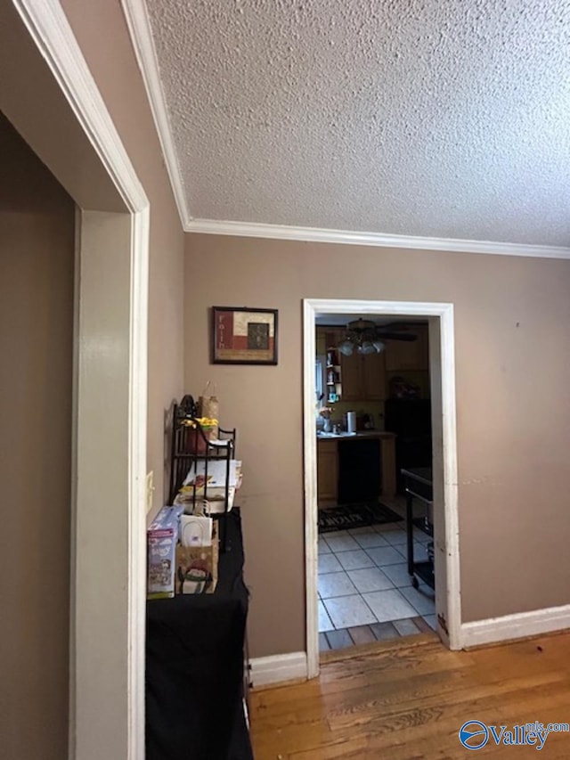 hall featuring hardwood / wood-style floors, crown molding, and a textured ceiling