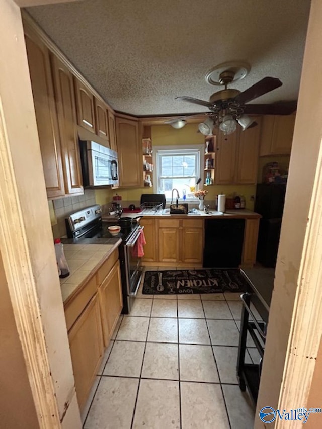 kitchen with light tile patterned floors, ceiling fan, stainless steel appliances, a textured ceiling, and tile countertops