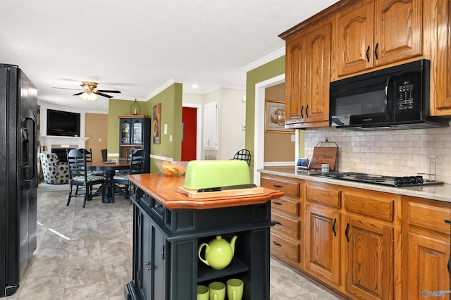 kitchen with black appliances, ceiling fan, decorative backsplash, ornamental molding, and a kitchen island