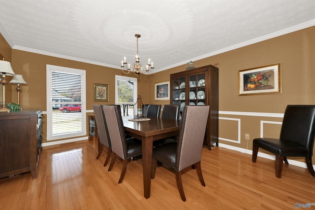 dining area featuring an inviting chandelier, light hardwood / wood-style flooring, and ornamental molding