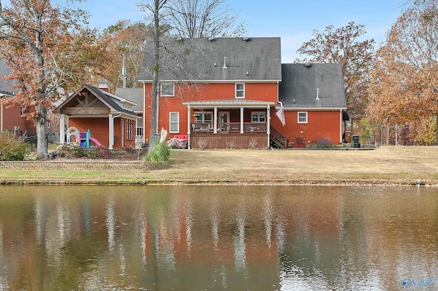 back of house with a lawn, central air condition unit, and a water view