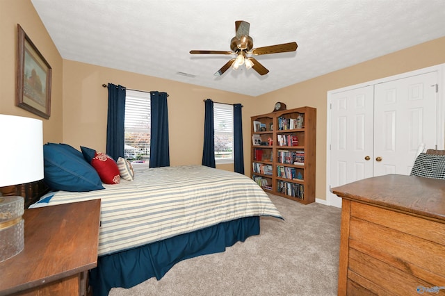 carpeted bedroom with a textured ceiling, a closet, and ceiling fan