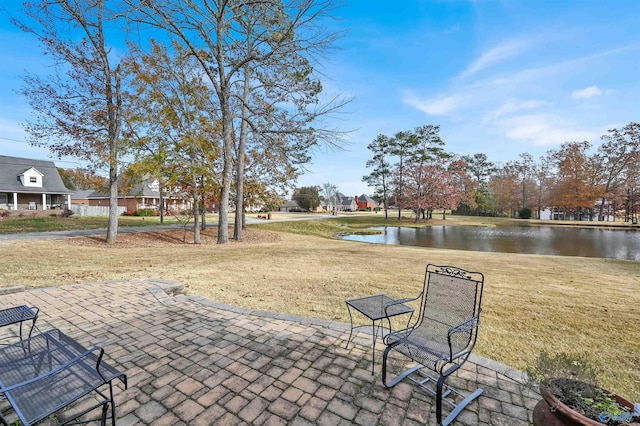 view of community featuring a water view, a patio area, and a lawn