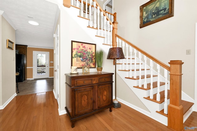 stairway with hardwood / wood-style flooring and ornamental molding