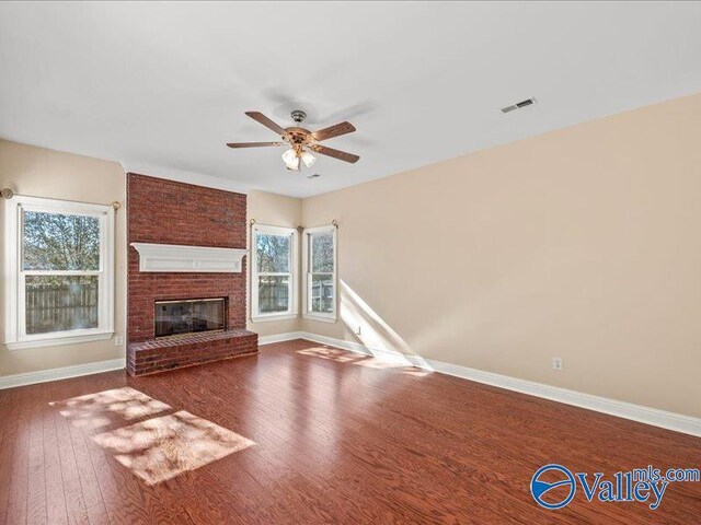 unfurnished living room featuring wood-type flooring, a brick fireplace, and ceiling fan