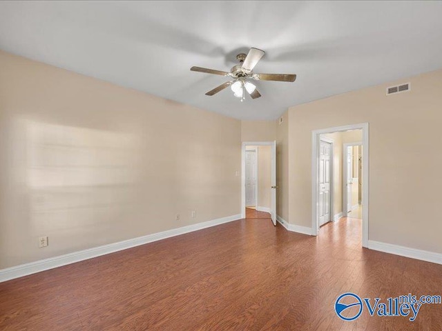 empty room with ceiling fan and dark hardwood / wood-style flooring