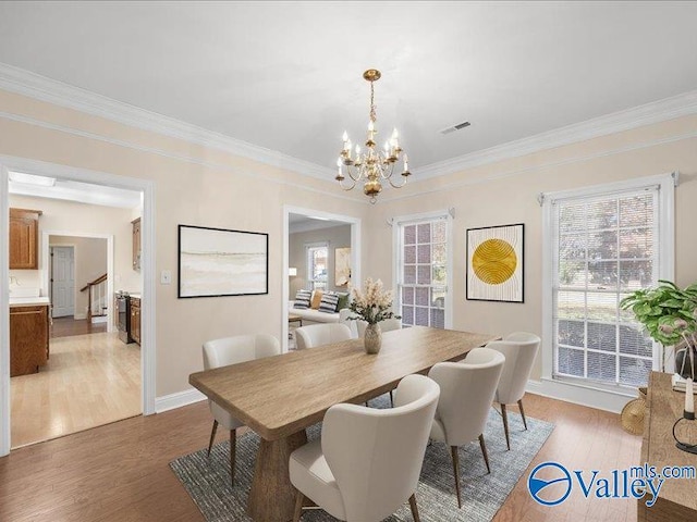 dining room featuring a chandelier, light wood-type flooring, and ornamental molding