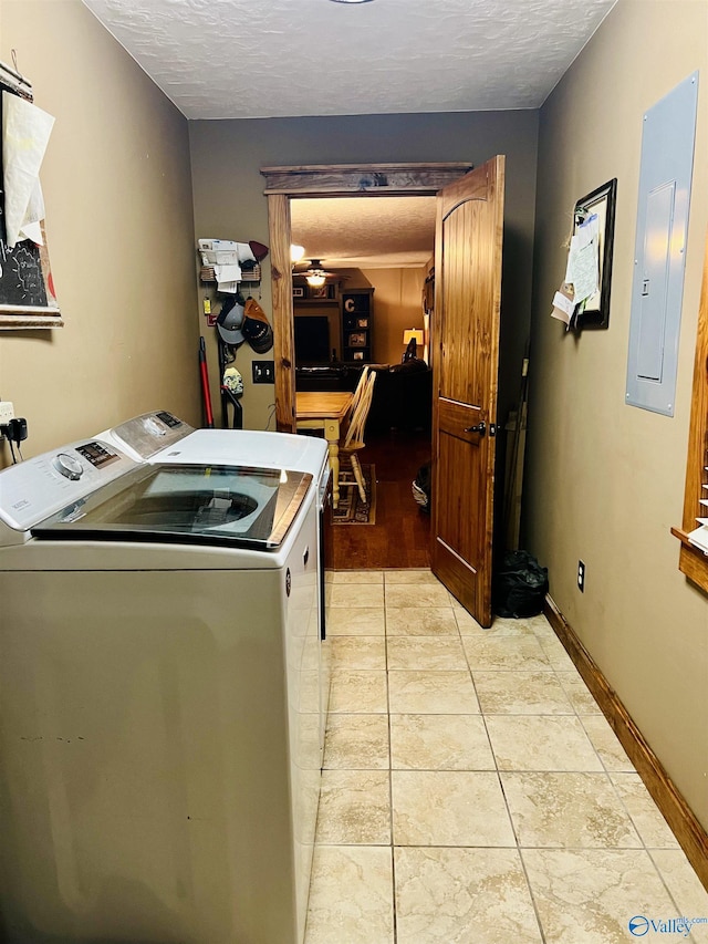 laundry room featuring electric panel, a textured ceiling, washing machine and dryer, baseboards, and laundry area