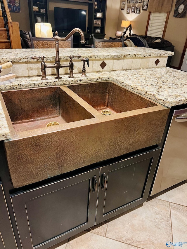 details with light stone countertops, dark cabinetry, and a sink