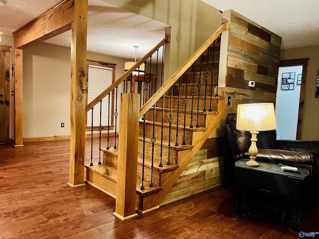 stairs featuring baseboards, a textured ceiling, and wood finished floors