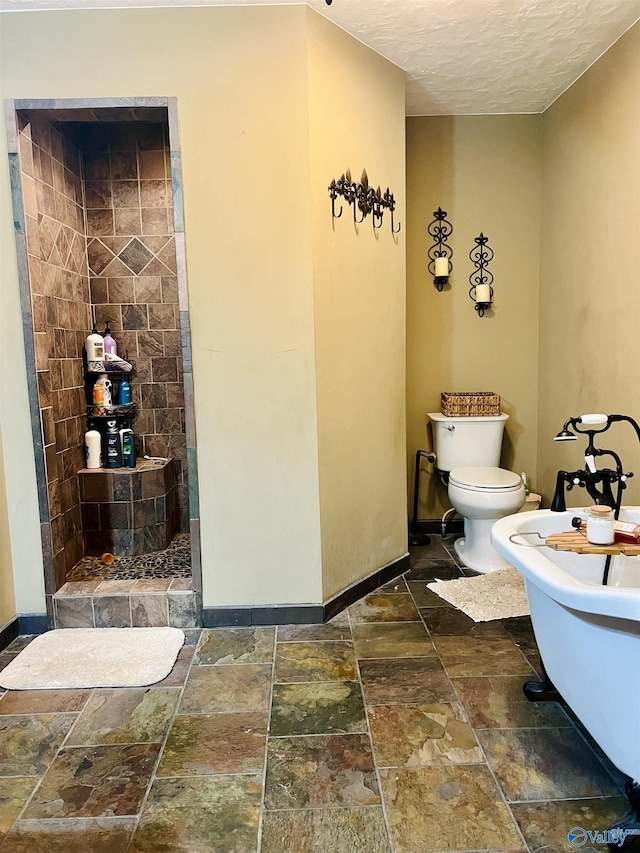 bathroom with a tile shower, toilet, baseboards, and stone tile flooring