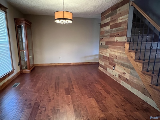 spare room with wood finished floors, visible vents, stairs, a textured ceiling, and a chandelier