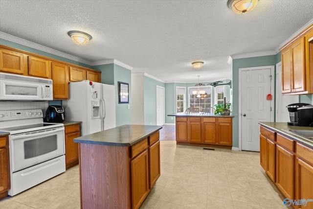 kitchen with ornamental molding, a center island, a chandelier, and white appliances