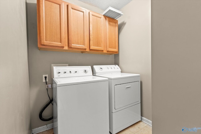 laundry area featuring cabinets, washing machine and clothes dryer, and light tile patterned flooring