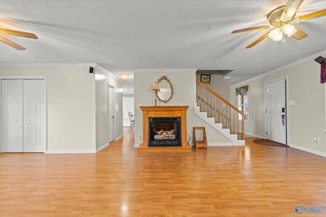 unfurnished living room with ceiling fan, crown molding, a textured ceiling, and light hardwood / wood-style floors