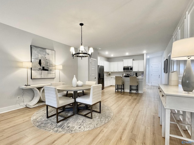 dining space with recessed lighting, baseboards, a notable chandelier, and light wood finished floors