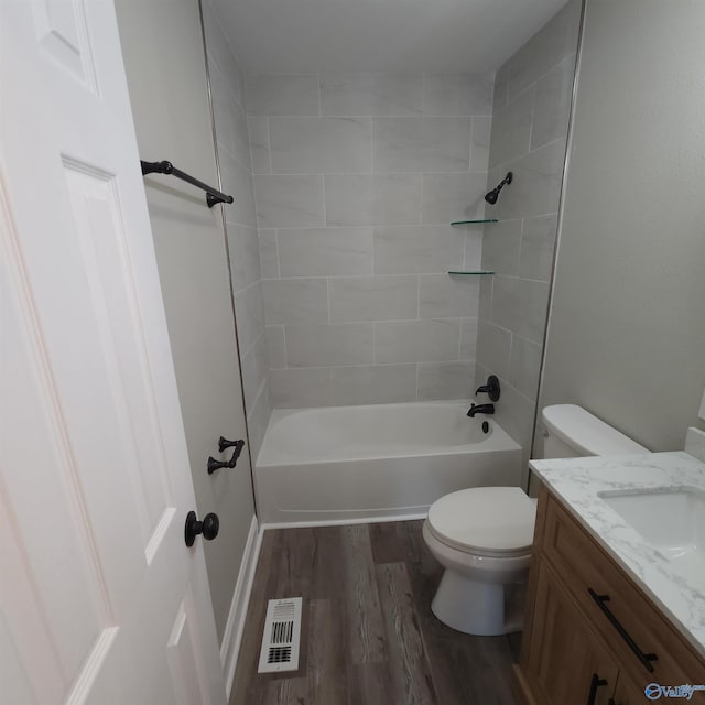 full bathroom with hardwood / wood-style floors, toilet, tiled shower / bath combo, and vanity