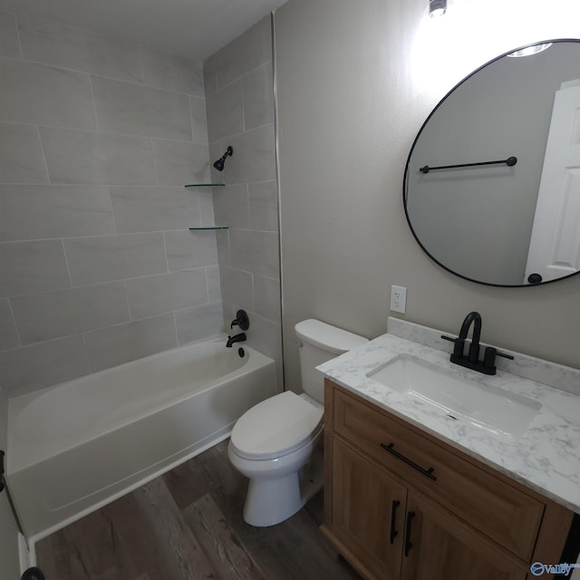 full bathroom with tiled shower / bath, toilet, hardwood / wood-style flooring, and vanity