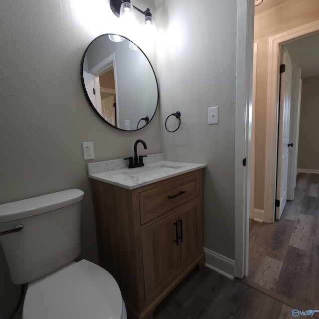 bathroom with vanity, toilet, and hardwood / wood-style floors