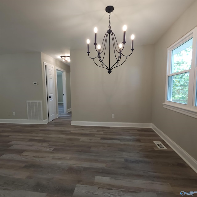 unfurnished dining area with dark wood-type flooring and a notable chandelier