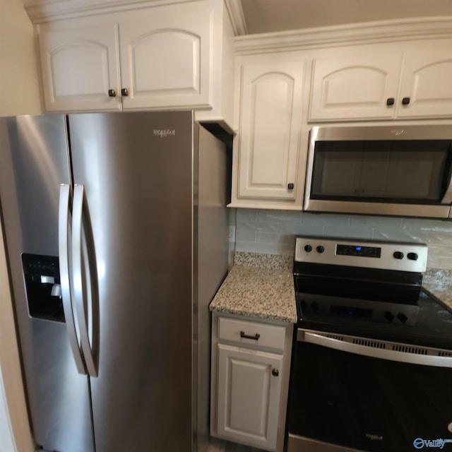 kitchen featuring white cabinets, light stone counters, stainless steel appliances, and tasteful backsplash