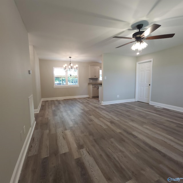 unfurnished living room featuring ceiling fan with notable chandelier and dark wood-type flooring