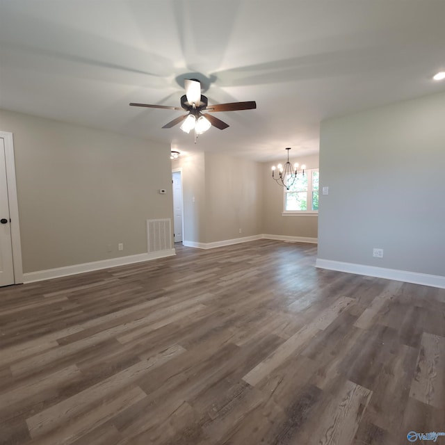 empty room featuring ceiling fan with notable chandelier and dark hardwood / wood-style flooring