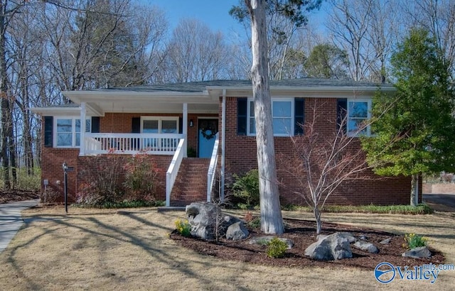 view of front of home with stairs, brick siding, and a porch