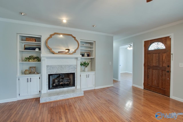 unfurnished living room with ornamental molding, a premium fireplace, light wood-style flooring, and built in features