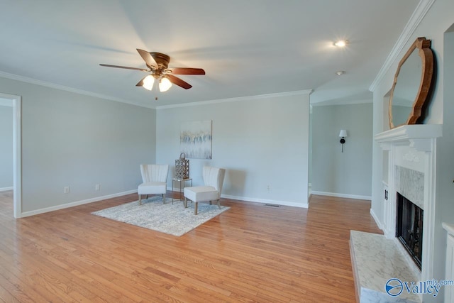 unfurnished room with a fireplace, a ceiling fan, baseboards, light wood-style floors, and ornamental molding