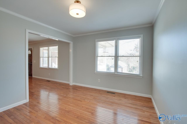 spare room with baseboards, ornamental molding, visible vents, and light wood-style floors