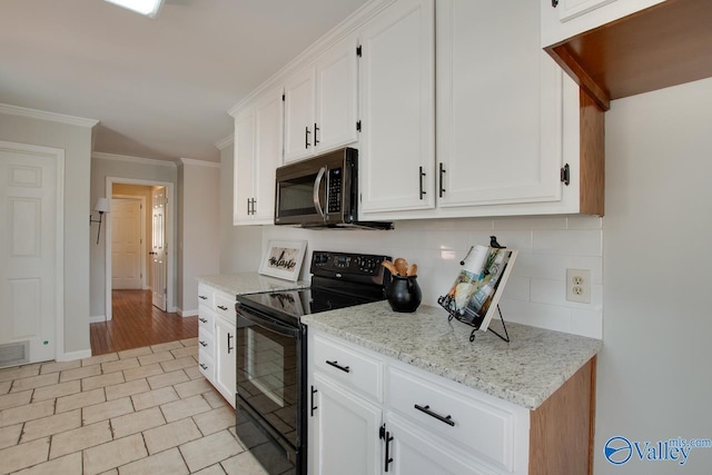 kitchen with white cabinets, stainless steel microwave, backsplash, and black range with electric stovetop