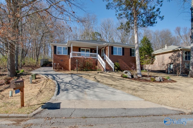 ranch-style home with concrete driveway, a porch, crawl space, and brick siding