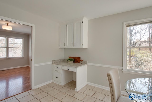 interior space with plenty of natural light, baseboards, and white cabinets