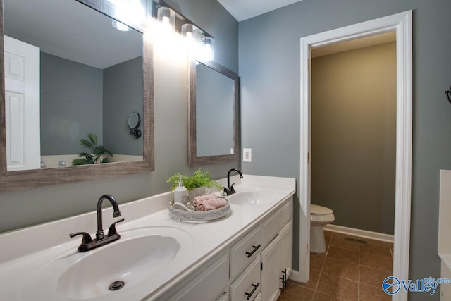 bathroom with toilet, tile patterned flooring, double vanity, and a sink