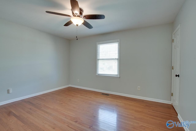 spare room with light wood finished floors, a ceiling fan, visible vents, and baseboards