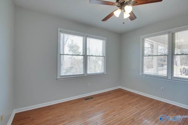 unfurnished room featuring hardwood / wood-style floors, a ceiling fan, visible vents, and baseboards