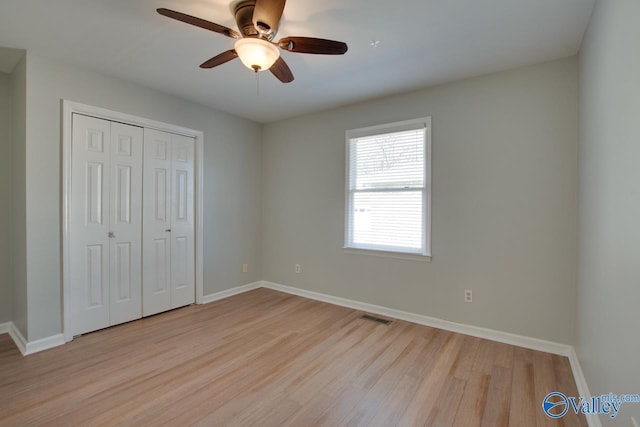 unfurnished bedroom with a closet, visible vents, baseboards, and wood finished floors