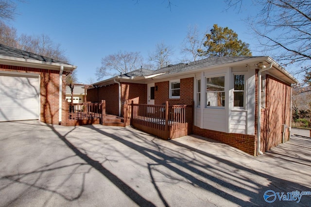 view of front of property with a garage, brick siding, and a wooden deck