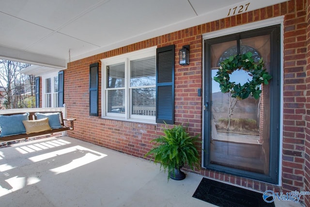 entrance to property featuring covered porch and brick siding