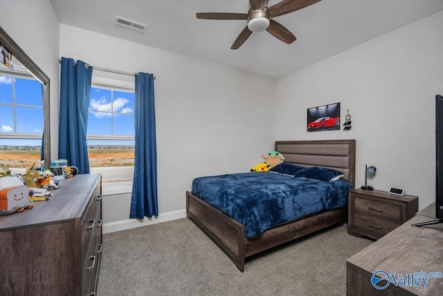 bedroom with multiple windows, ceiling fan, and light carpet