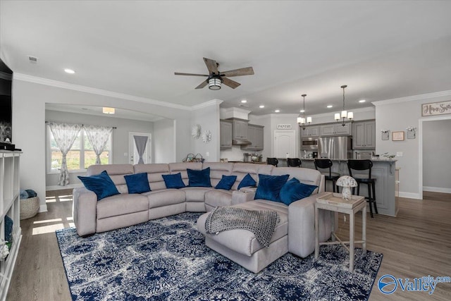 living room with ceiling fan with notable chandelier, dark hardwood / wood-style floors, and crown molding