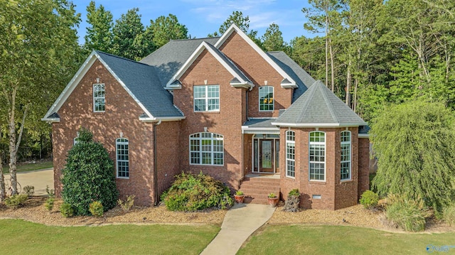 traditional home featuring crawl space, brick siding, a front lawn, and roof with shingles