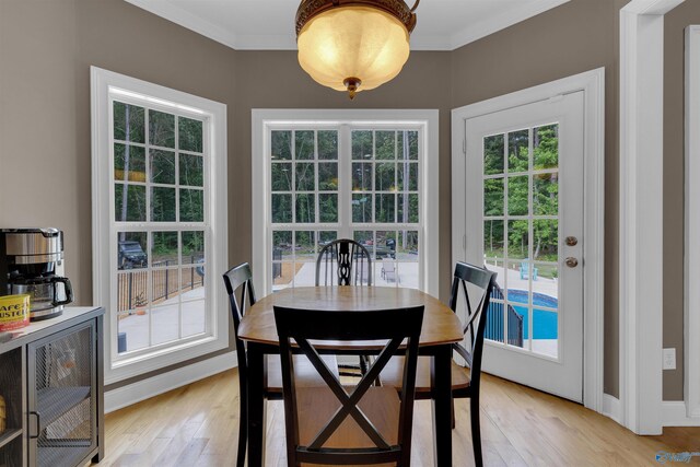 dining space featuring plenty of natural light, ornamental molding, and light hardwood / wood-style floors