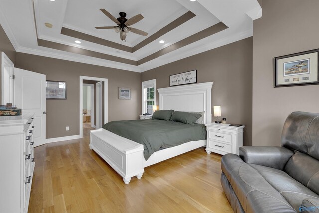 bedroom featuring ornamental molding, ceiling fan, light wood-type flooring, and a tray ceiling