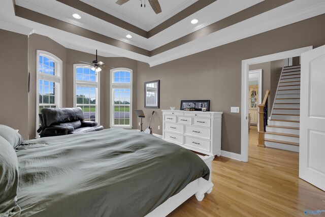 bedroom with ceiling fan, light hardwood / wood-style flooring, ornamental molding, and a tray ceiling