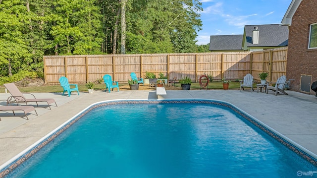 view of pool with a fenced backyard, a diving board, a fenced in pool, and a patio