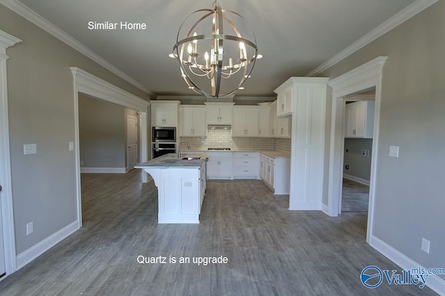 kitchen featuring an inviting chandelier, built in microwave, a sink, white cabinets, and tasteful backsplash